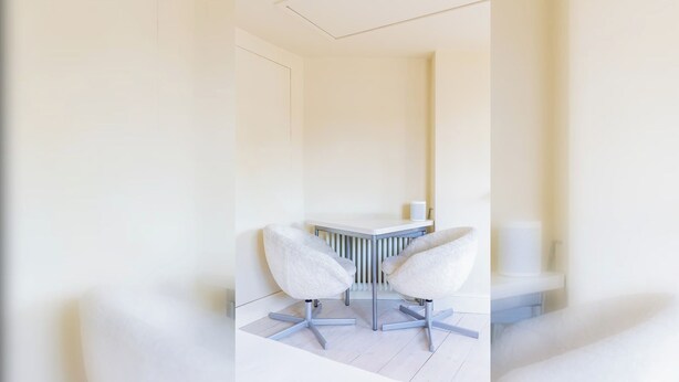 Habitació moderna i minimalista amb escriptori blanc i dues cadires.