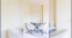 Ein moderner, minimalistischer Raum mit einem weißen Schreibtisch und zwei Stühlen.