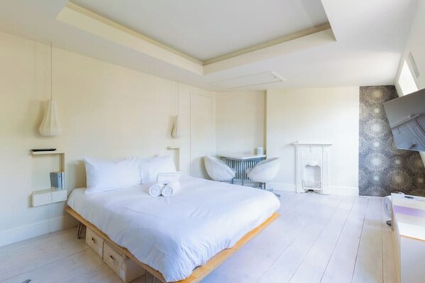 Ein Schlafzimmer mit einem großen Bett, Nachttischen, einem Schreibtisch und einem Stuhl.