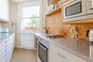 Et moderne køkken med rustfrie stålgadgetter, et vindue med udsigt til grønt og en backsplash i fiskebensmønstret træ.