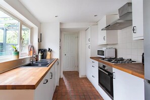 Kitchen with white cabinetry, wooden countertop, and stainless steel range hood.