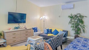 A living room with a sofa, a small table, a TV, a lamp, and a potted plant.