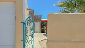 A gated entrance with a metal gate, a white door, and a building with a modern design.