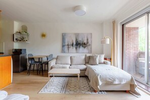 A modern living room with a sofa, a dining table, and a kitchen area. - Cosy Refurbished Studio w Pvt Balcony Kensington (London)
