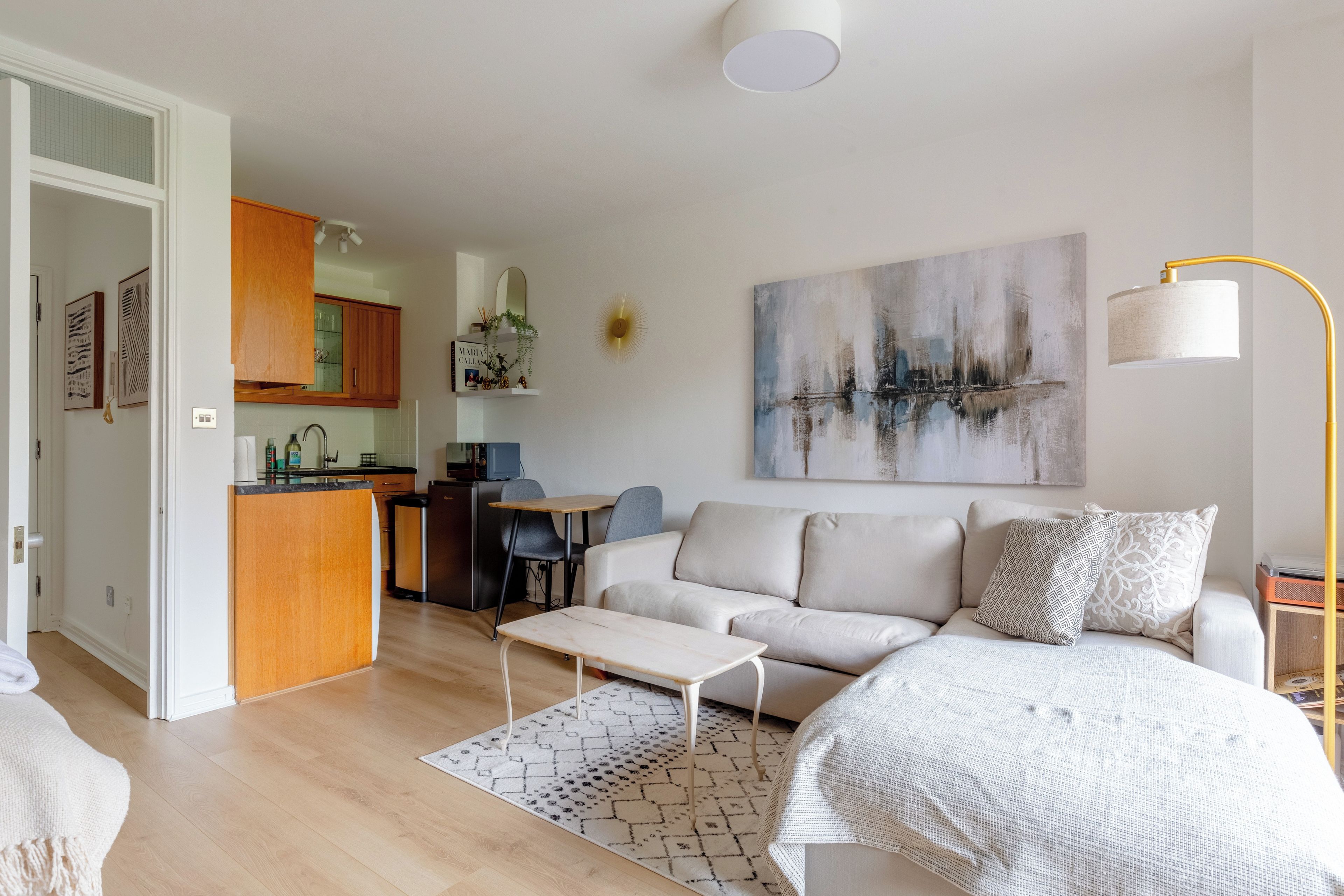 En moderne stue med sofa, sofabord og et billede på væggen.