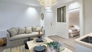 Un salon moderne avec un canapé, une table à manger et un grand luminaire suspendu au design élégant.