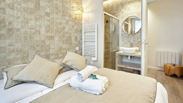 Une chambre d’hôtel avec un grand lit, une salle de bain équipée d’un lavabo et d’un miroir, ainsi qu’un espace douche.