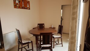 Un comedor con una mesa redonda de madera y cuatro sillas, un radiador blanco y un cuadro en la pared.