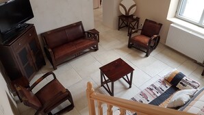 Una sala de estar con sofá, sillas, una mesa de centro, televisión y ventana con vistas.