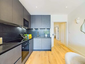 Una cocina moderna con armarios oscuros, un lavamanos de acero inoxidable y piso de madera.