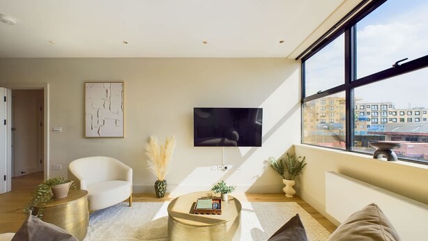 Ein modernes Wohnzimmer mit Sofa, Couchtisch, Fernseher und großen Fenstern.
