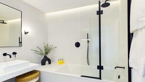 Ein modernes Badezimmer mit einer Duschkabine, einem weißen Waschbecken und einem Spiegel.
