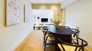A dining area with a round table, chairs, and artwork on the walls.