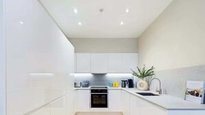 A modern kitchen with white cabinets, a wooden floor, and a built-in oven.
