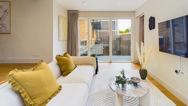 A modern living room with a sofa, a coffee table, and a large window with a view of a building.