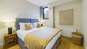 A bedroom with a bed, bedside tables, a window, and a wall-mounted artwork.