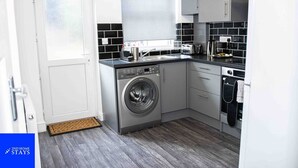 A compact kitchen with a washing machine, a sink, and a stove.