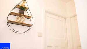 A white wall with a metal shelf holding a plant and two rings.