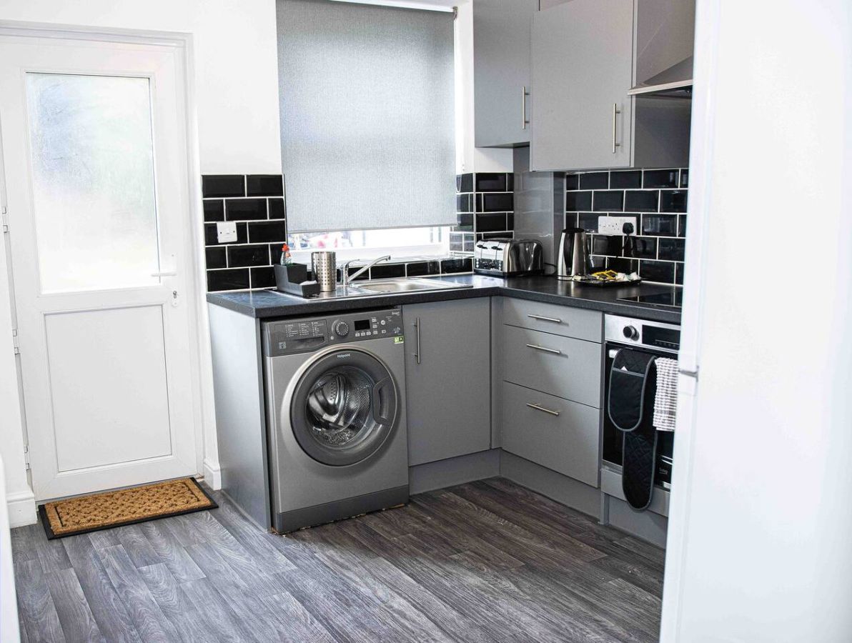 A compact kitchen with a washing machine, a sink, and a stove.