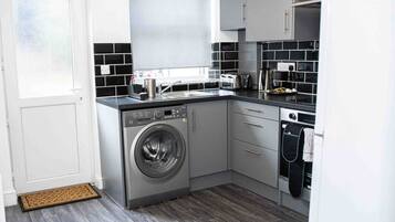 A compact kitchen with a washing machine, a sink, and a stove.