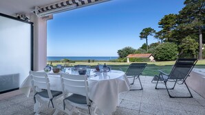 A covered patio with a table set for dining, outdoor chairs, and a view of the sea. - Seaside. for 4 people. in Pornic (Pornic)