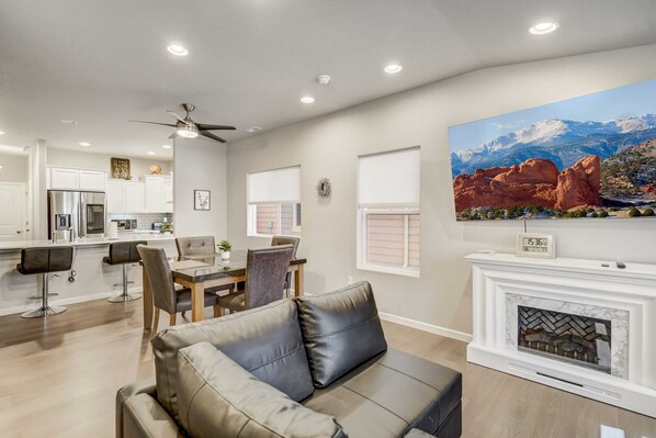 A modern living room with a fireplace, dining area, and kitchen. - 2BR w Swing bench Porch & BBQ | Garden of the Gods (Colorado Springs)