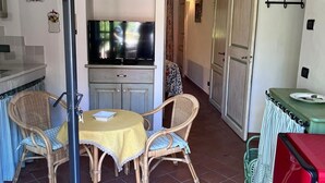 A compact kitchen with a TV, wicker chairs, a small dining table, and a red refrigerator. - XIV Century Nest in Ancient Palagio - Montecatini Alto (Montecatini Alto)