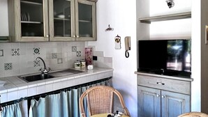 A compact kitchen with a dining area, featuring a built-in TV, a sink, and a small table with a yellow tablecloth. - XIV Century Nest in Ancient Palagio - Montecatini Alto (Montecatini Alto)