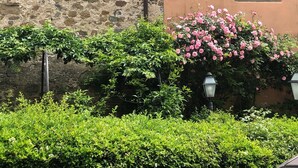 A stone wall with a brick ledge, a pink flowering bush, and a street lamp. - XIV Century Nest in Ancient Palagio - Montecatini Alto (Montecatini Alto)