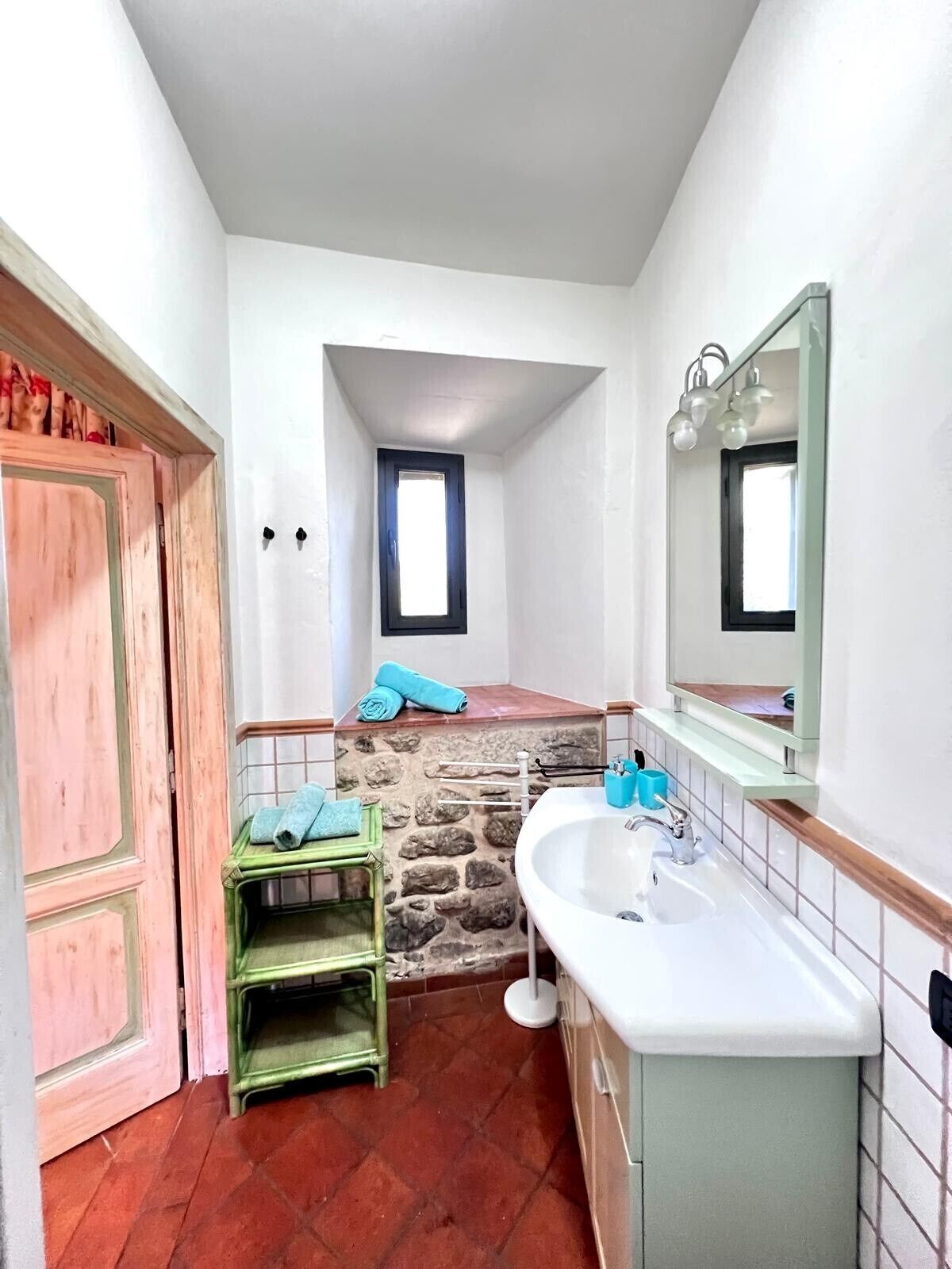 Un baño pequeño con una pared de acento de piedra, un lavamanos, un espejo y una puerta.
