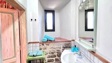 Un baño pequeño con una pared de acento de piedra, un lavamanos, un espejo y una puerta.