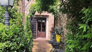 A narrow brick pathway leading to a door with a stone wall on one side and a metal fence on the other. - XIV Century Nest in Ancient Palagio - Montecatini Alto (Montecatini Alto)