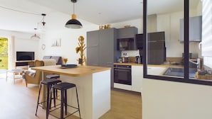 Een moderne keuken met een centraal eiland, een eetgedeelte met barstoelen en een televisie in de woonkamer.