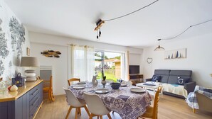 Een eetgedeelte met een tafel voor vier personen, een bank en een televisie in een woonkamer.