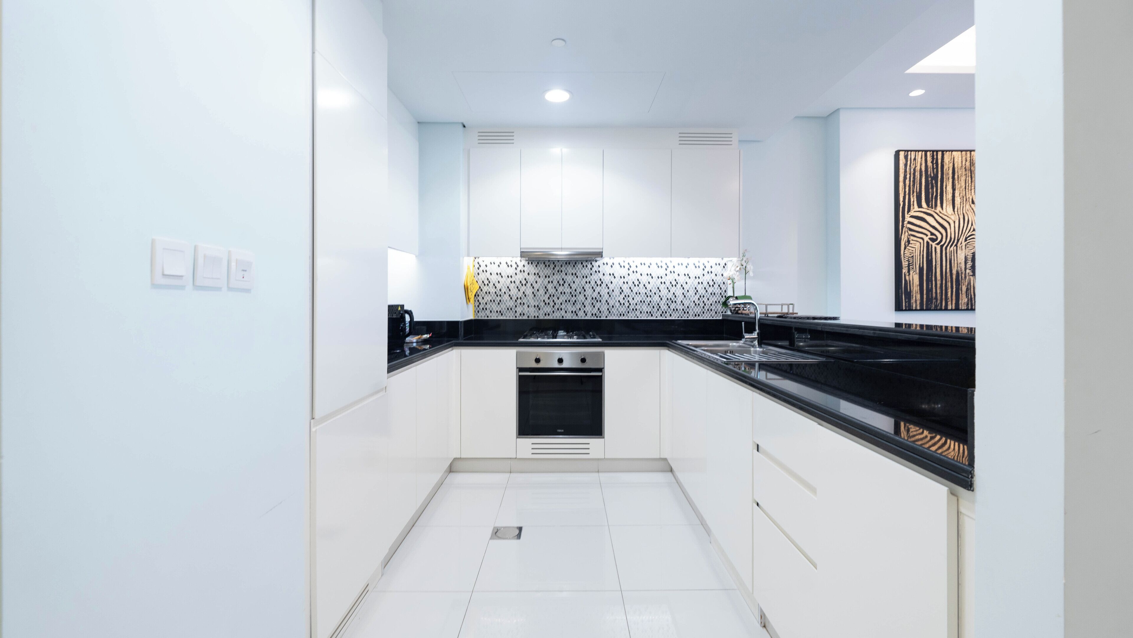 Una cocina moderna con armarios blancos, encimera negra y salpicadero con diseño.