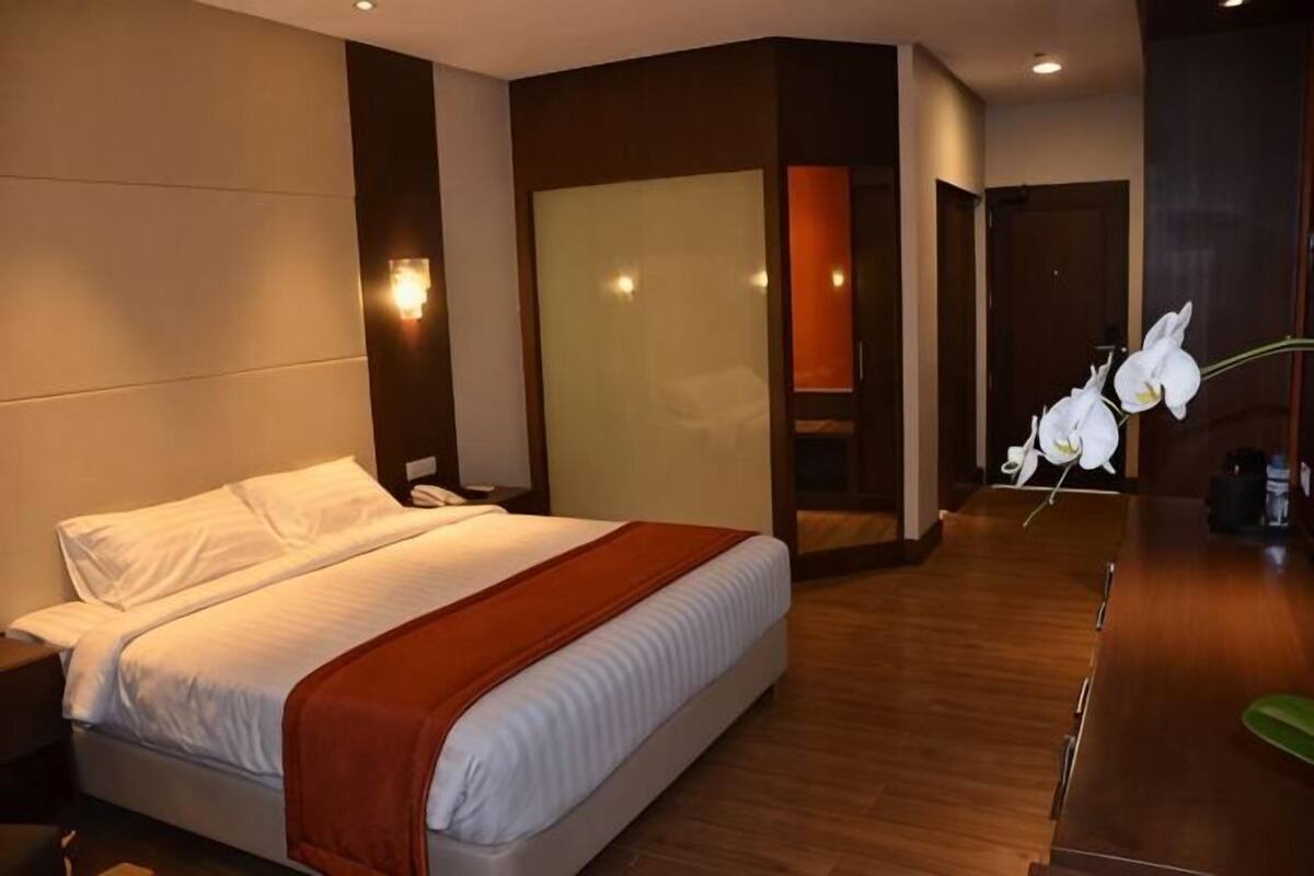 Ein Hotelzimmer mit Bett, Nachttisch und einem großen Spiegel.