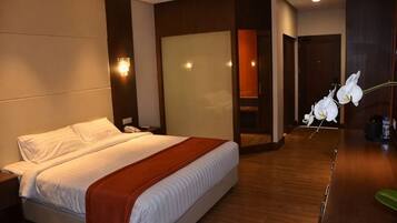 A hotel room with a bed, nightstand, and a large mirror.