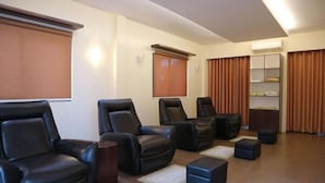 A room with black leather recliners, a small wooden table, and a shelf with items. - Hotel Monticello Tagaytay (Tagaytay)