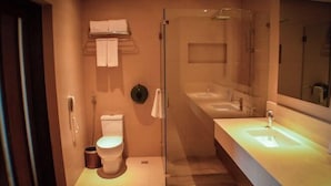 A modern bathroom with a glass-enclosed shower, a white toilet, and a large sink with a mirror. - Hotel Monticello Tagaytay (Tagaytay)