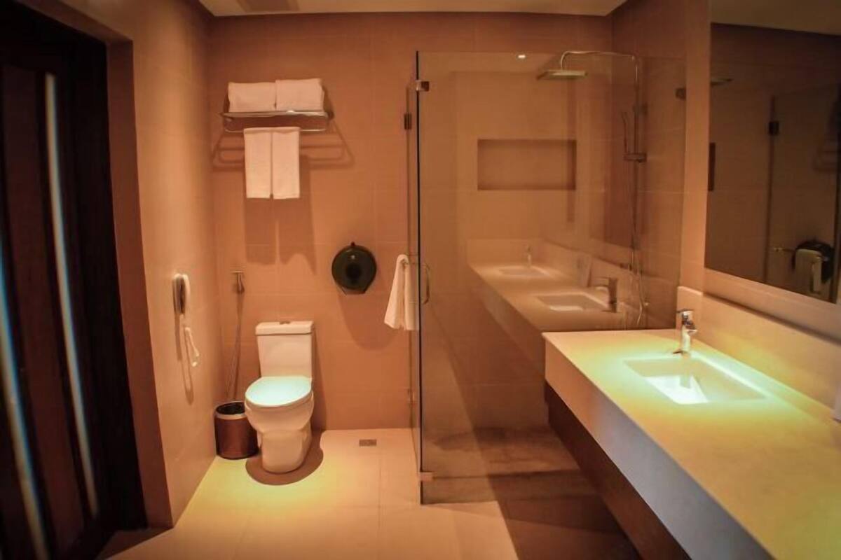 Ein modernes Badezimmer mit einer gläsernen Duschkabine, einer weißen Toilette und einem großen Waschbecken mit Spiegel.