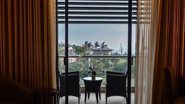 A room with a view through a sliding door, featuring a small table and two chairs. - Hotel Monticello Tagaytay (Tagaytay)
