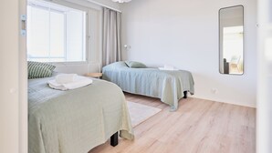 A bedroom with two beds, a large window, a mirror, and a wooden floor. - Forenom Serviced Apartments Klaukkala (Nurmijärvi)