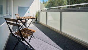 A balcony with foldable wooden chairs and a potted plant. - Forenom Serviced Apartments Klaukkala (Nurmijärvi)