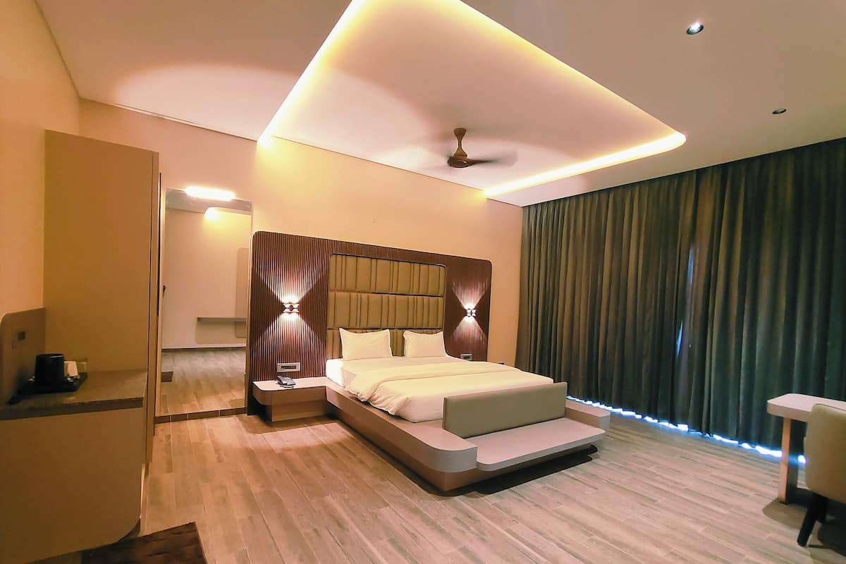 A modern hotel room with a large bed, a desk, and a ceiling fan.