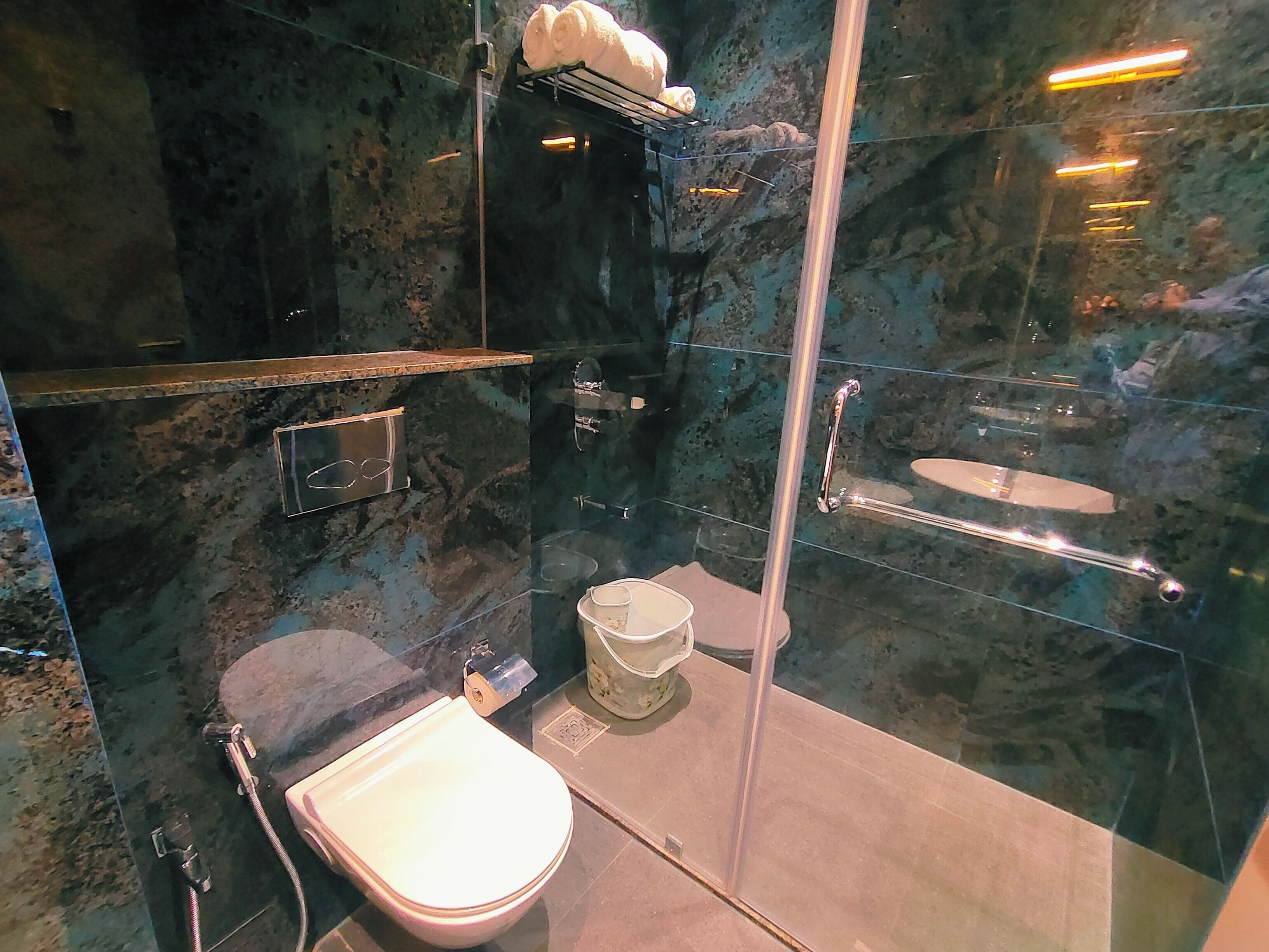 A modern bathroom with a glass-enclosed shower, a toilet, and a sink.