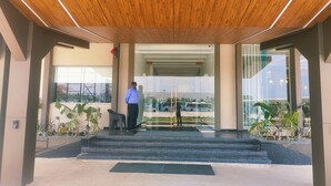A modern building entrance with a wooden ceiling, glass doors, and a staircase leading to the upper floor. - Hotel Akshay Palace (Ahmednagar)