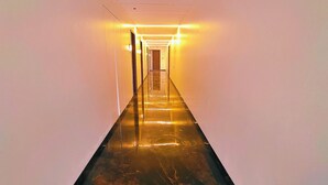 A long, narrow hallway with a shiny, reflective floor and bright overhead lighting. - Hotel Akshay Palace (Ahmednagar)