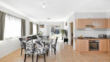 A modern kitchen with a gas stove, oven, and a dining area with a table and chairs.