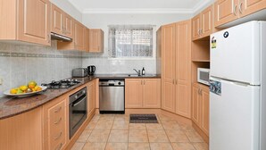 A kitchen with wooden cabinets, a gas stove, a dishwasher, and a refrigerator.