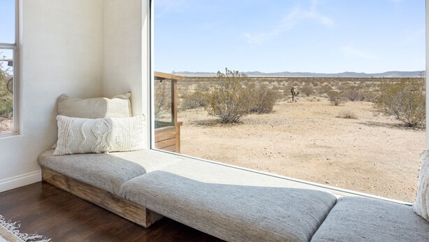 A room with a large window offering a view of a desert landscape. - Desert Moon - Serene Desert Views & Design 3 Bedroom Home by RedAwning (Joshua Tree)